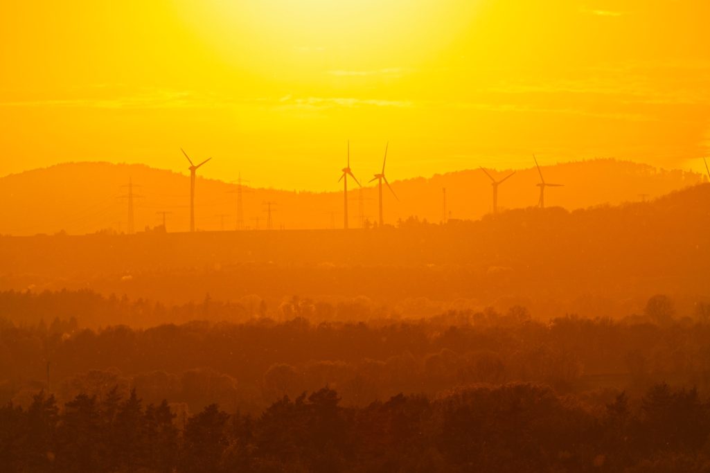Sonnenuntergang über den Bergen Sonnenuntergang über Hügeln mit Windkraftanlagen im Hintergrund.