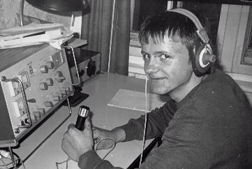 Junger Mann mit Kopfhörern, der an einem Radiogerät arbeitet.